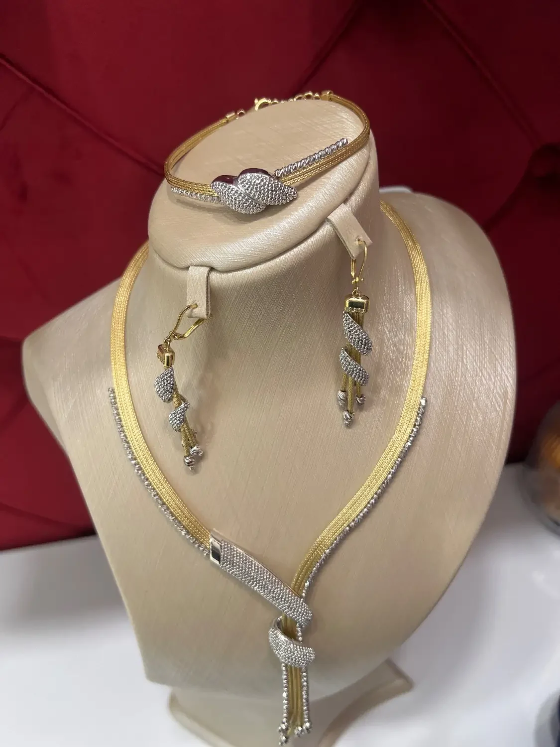 سرویس سرجیو شامل گردنبند، گوشواره و دستبند روی پایه نمایش با طراحی دو رنگ قابل مشاهده