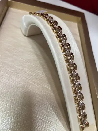 نمای نزدیک دستبند طلا رولکس تراش آینه‌ای روی پایه سفید داخل جعبه