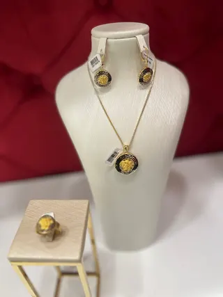 نیم‌ست ورساچه گلد شامل گردنبند و یک جفت گوشواره روی پایه نمایش، با طراحی دایره‌ای هماهنگ